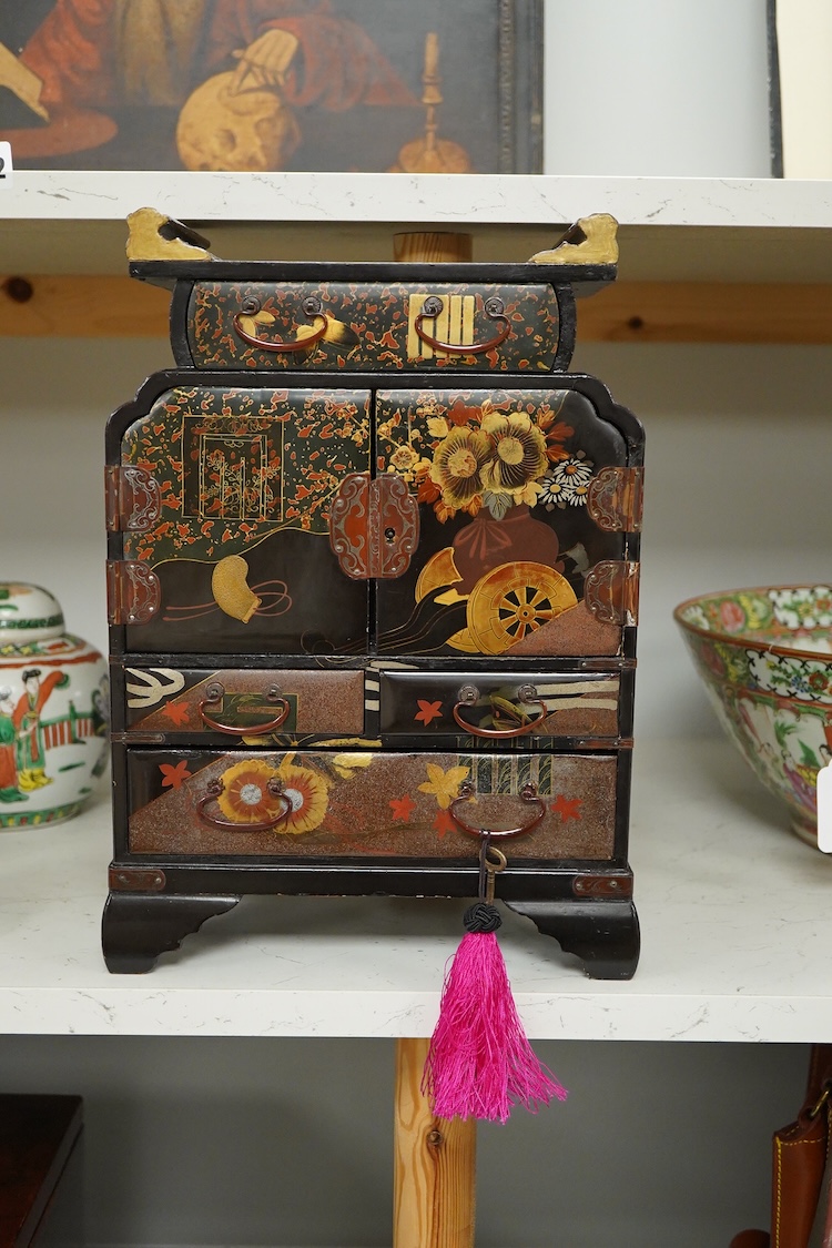 A Japanese gilt decorated black lacquer table cabinet, fitted with seven drawers, with key, 35cm high